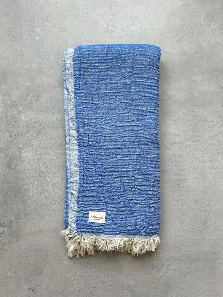 Textured Samos hammam towel in serene blue hues of Sea and Sky against a grey background by Bohemia Design