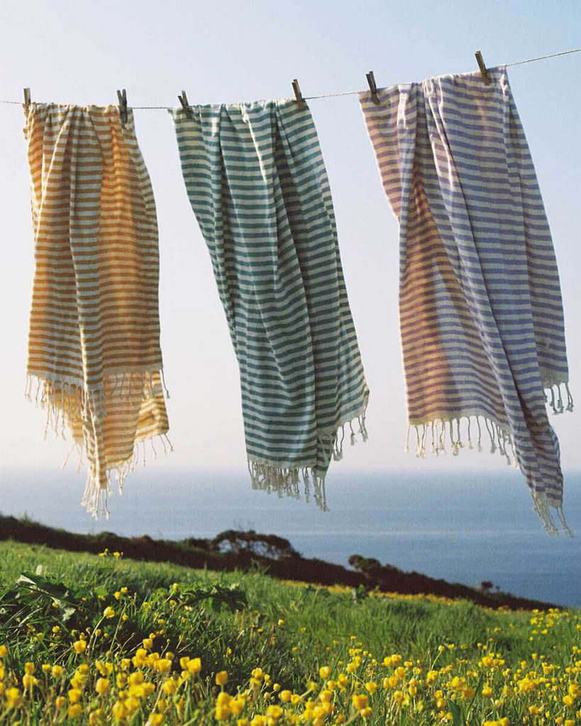 Three striped Sorrento hammam towels hanging on a line by the coast