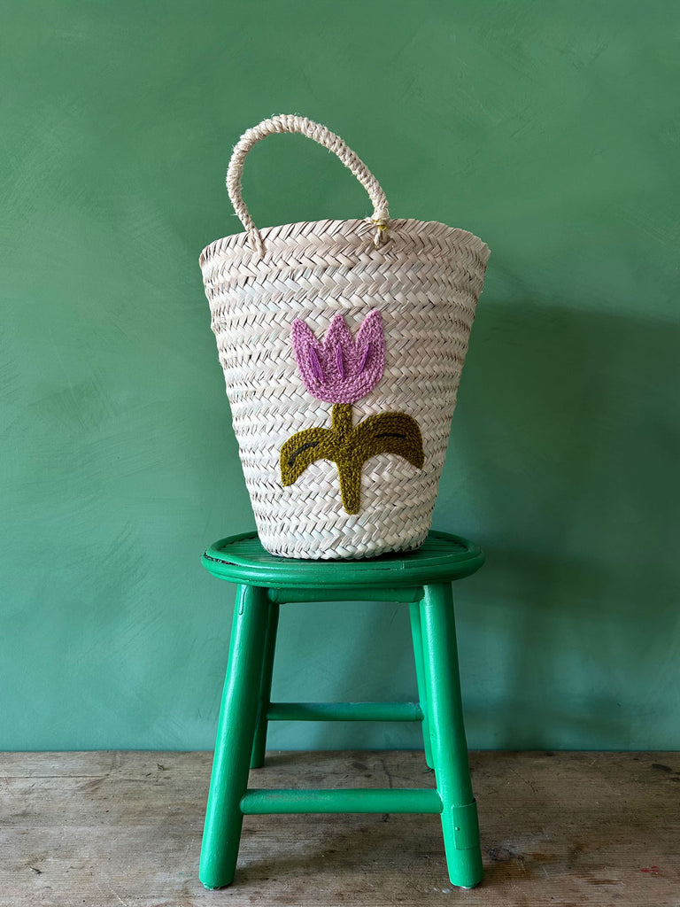 Hand embroidered bucket basket with a Tulip motif on a green stool against a green wall | Bohemia Design