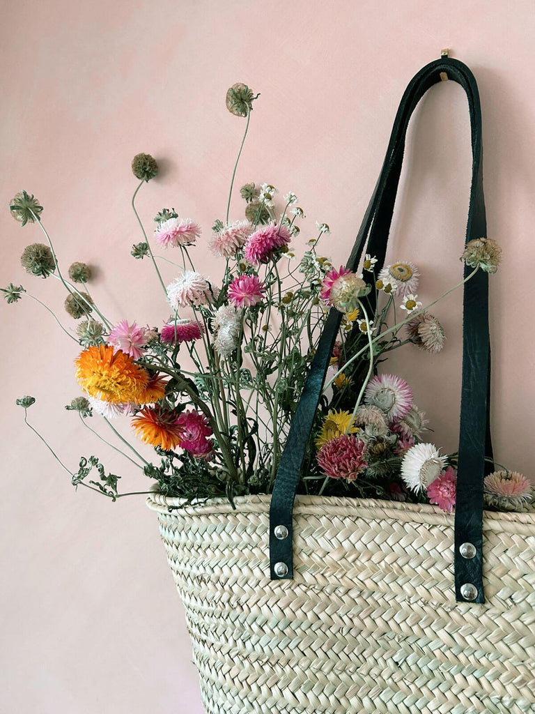 A Valencia basket with black leather handles filled with dried flowers
