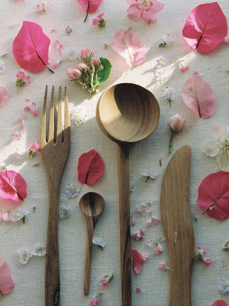 Walnut Wood Fork, spoon and knife surrounded by pink flower petals
