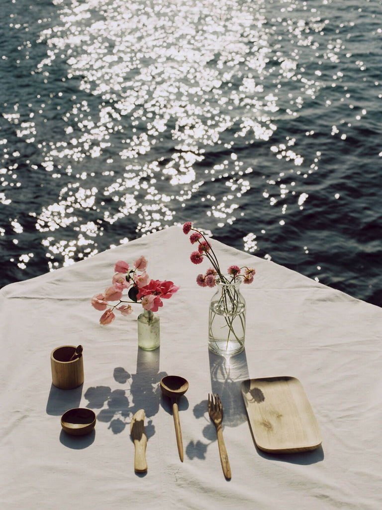 Walnut wood tray alongside other handcrafted wood cutlery on a table setting by the sea
