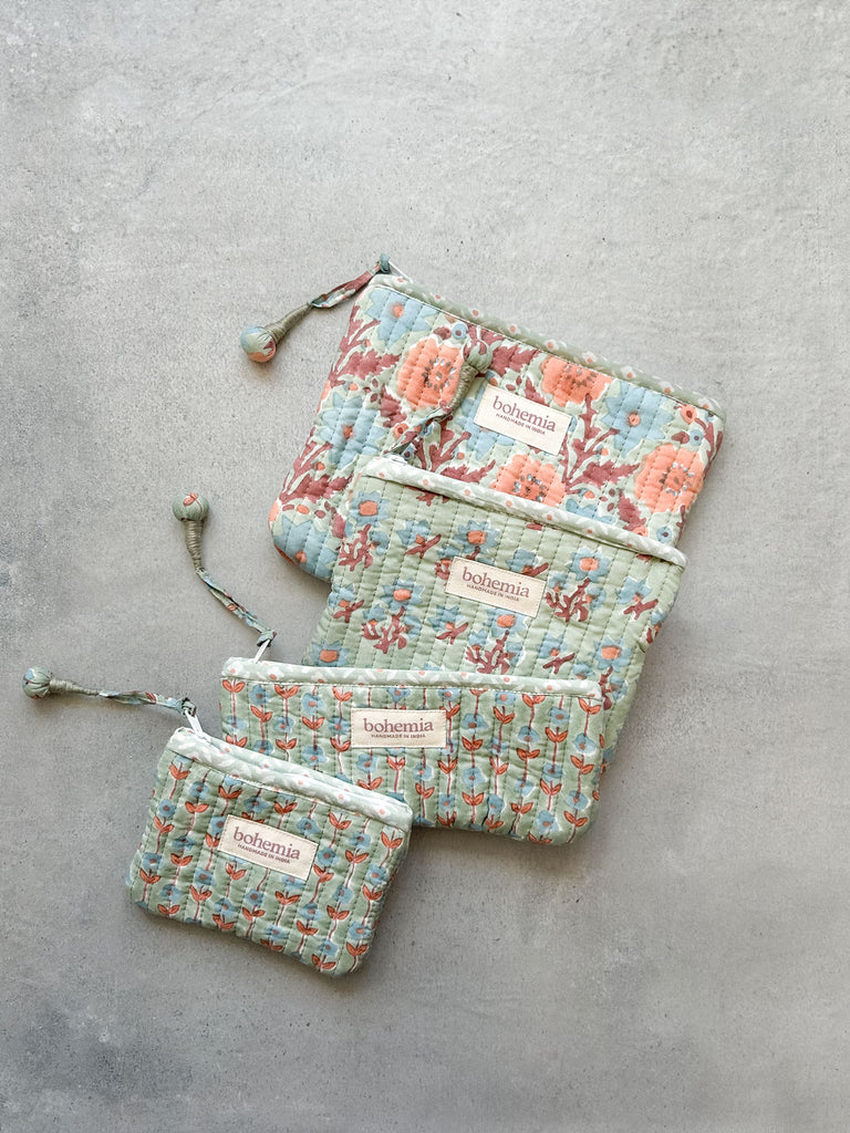 Four zip pouches with blue and terracotta flowers hand block printed on a soft green by Bohemia Design