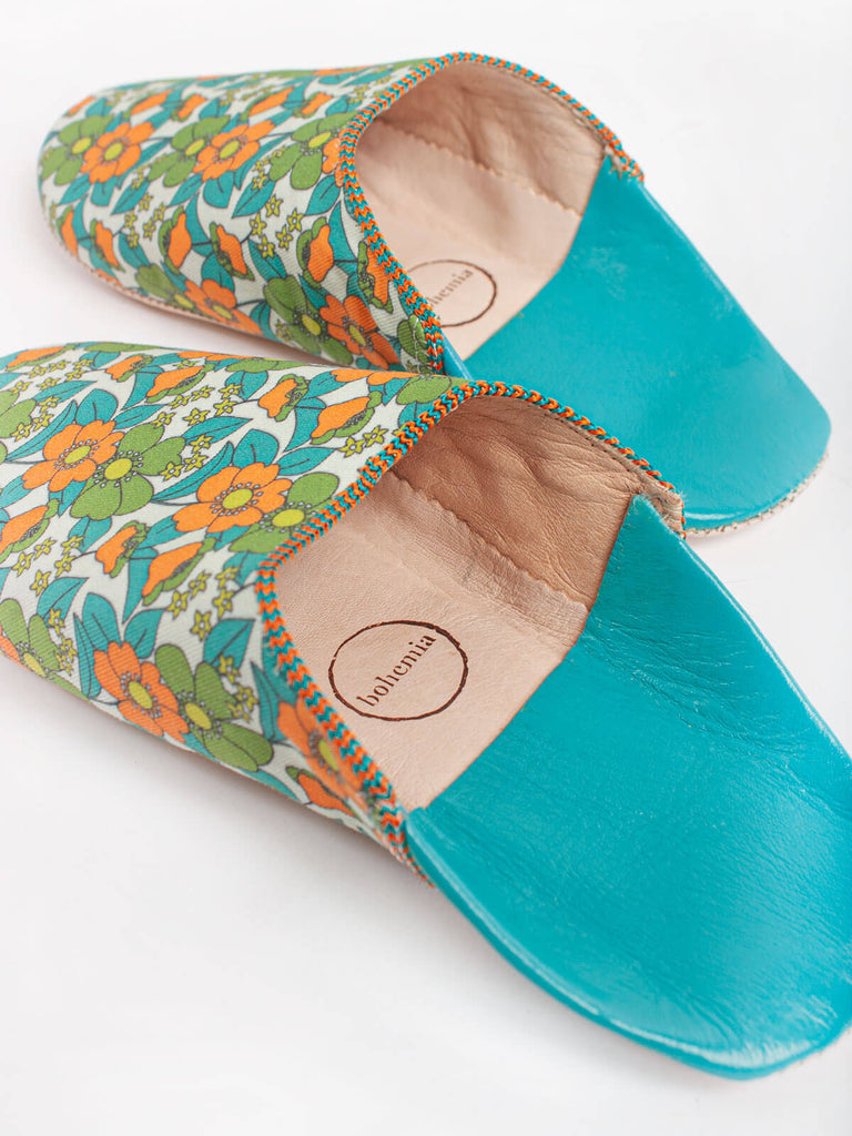 A pair of Moroccan babouche slippers in an aqua and orange floral pattern by Bohemia Design