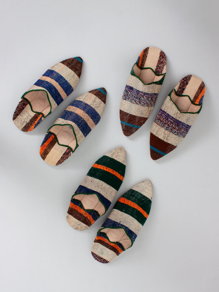 A group of three pairs of Moroccan pointed slippers handmade from natural leather and vintage striped boujad fabric, each pair is unique in pattern.
