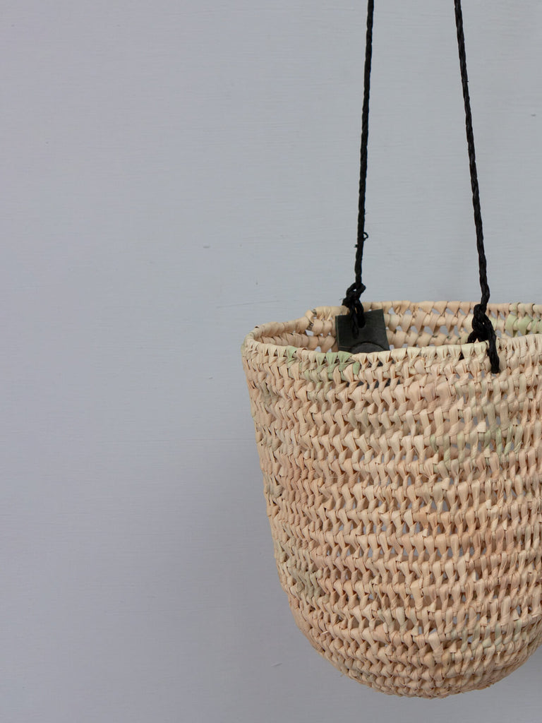 A close up of an open weave dome hanging basket showing the black leather thong and Bohemia label
