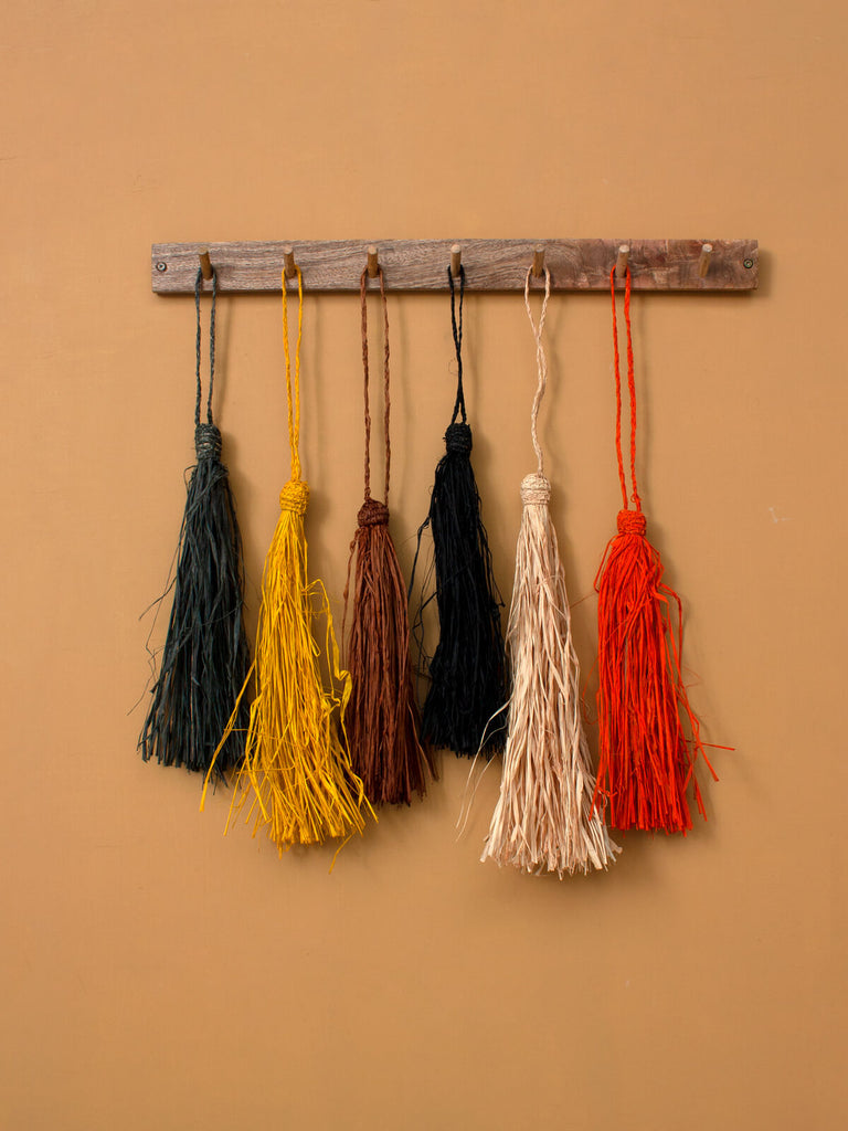 Raffia Tassels in different colours hanging together on wooden hooks