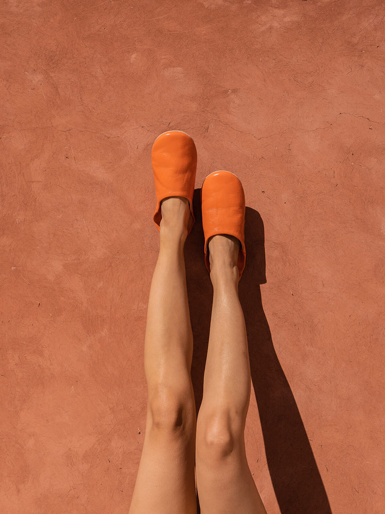 Bohemia-design-Moroccan-babouche-slippers-leather-tangerine-model-against-terracotta-wall