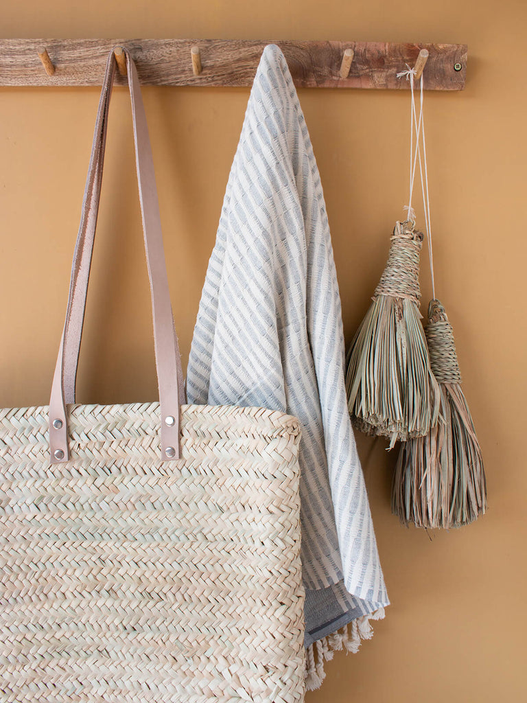 Asilah shopper basket hanging with hammam towel on hooks against a mustard wall