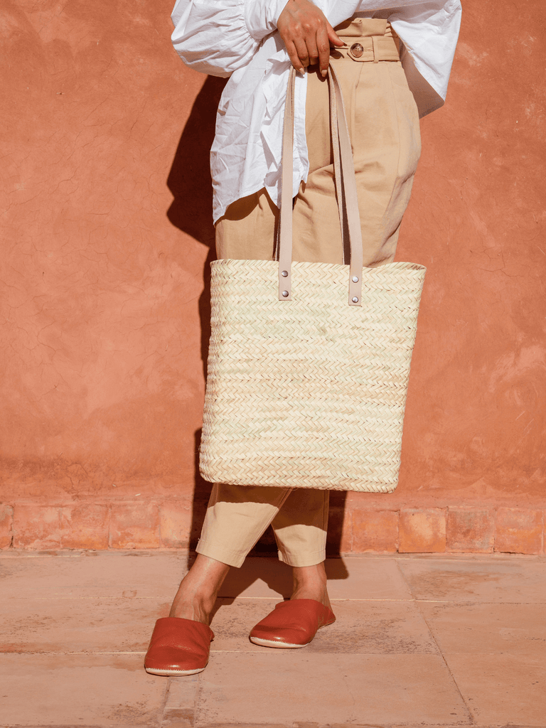 Woman holding Asilah shopper basket by Bohemia design against a terracotta wall