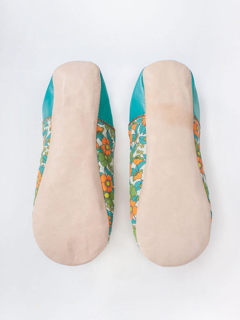 Underside of a pair of Moroccan babouche slippers in an aqua and orange floral pattern by Bohemia Design