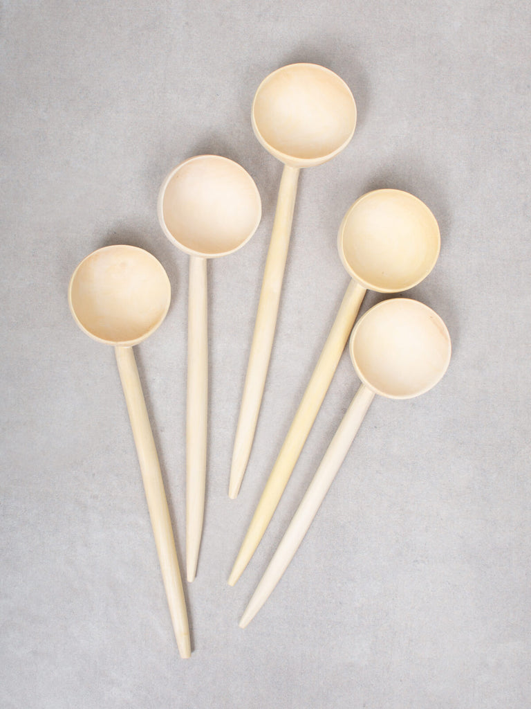 Five large lemon wood spoons on a grey background