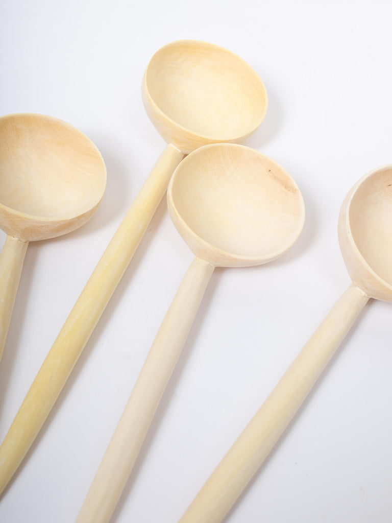 Group of four lemon wood spoons on a white background
