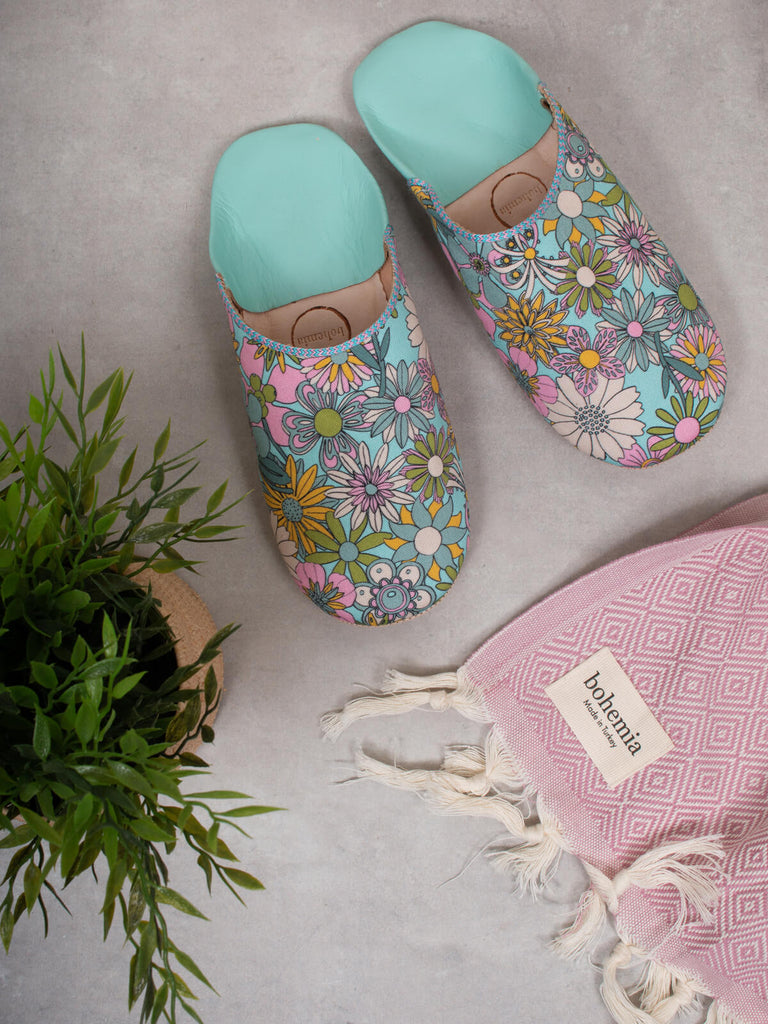 Margot Floral Babouche Slippers sitting beside a Bohemia Hammam Towel and plant.
