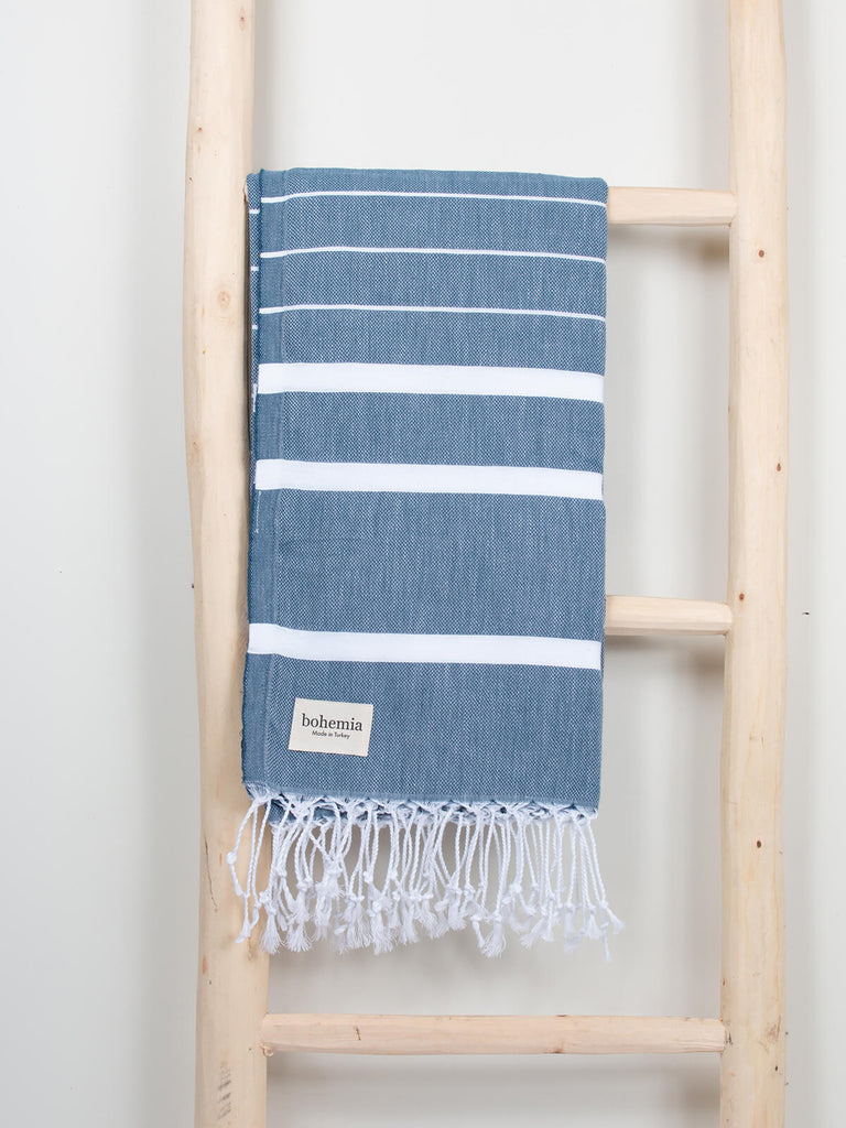 Ibiza Summer Hammam Towel in indigo stripe pattern by Bohemia Design hanging on a wooden ladder