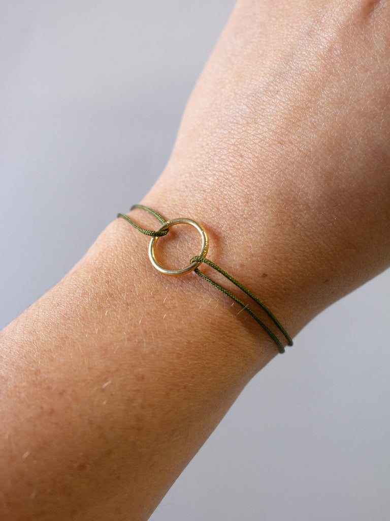 Woman wearing Gold juno bracelet with olive silk thread