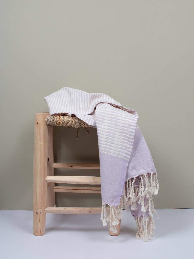 Lilac Turkish Hammam Towel by Bohemia Design draped on a woven stool