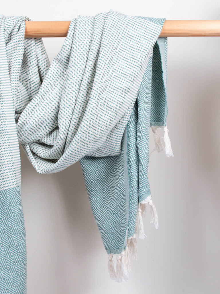 Nordic Dot Hammam Towel in grey green diamond pattern by Bohemia Design hanging on a wooden rod