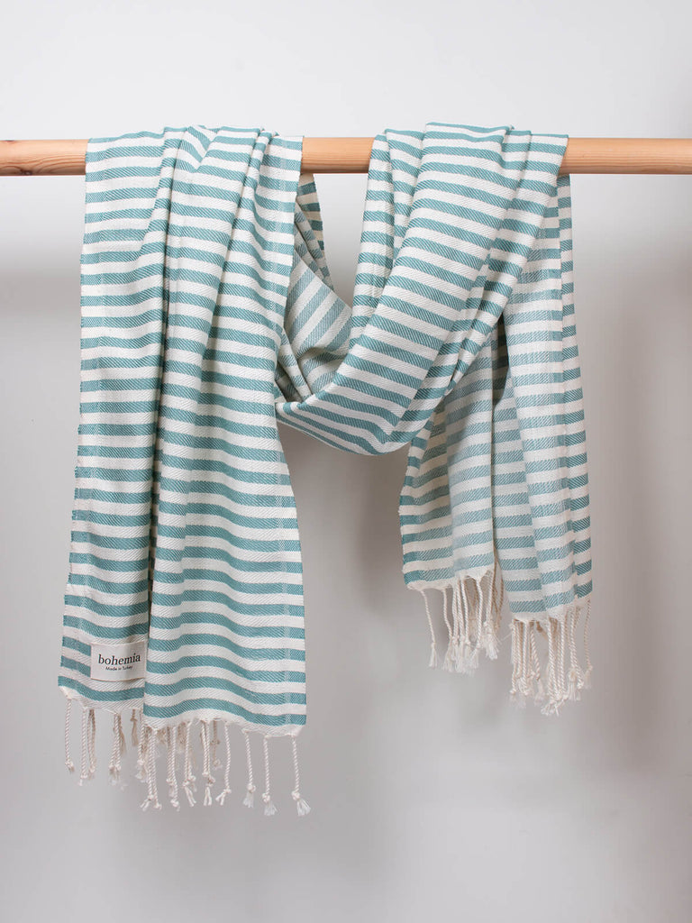 Striped Sorrento Hammam Towel in grey green stripe by Bohemia Design hanging on a wooden rod